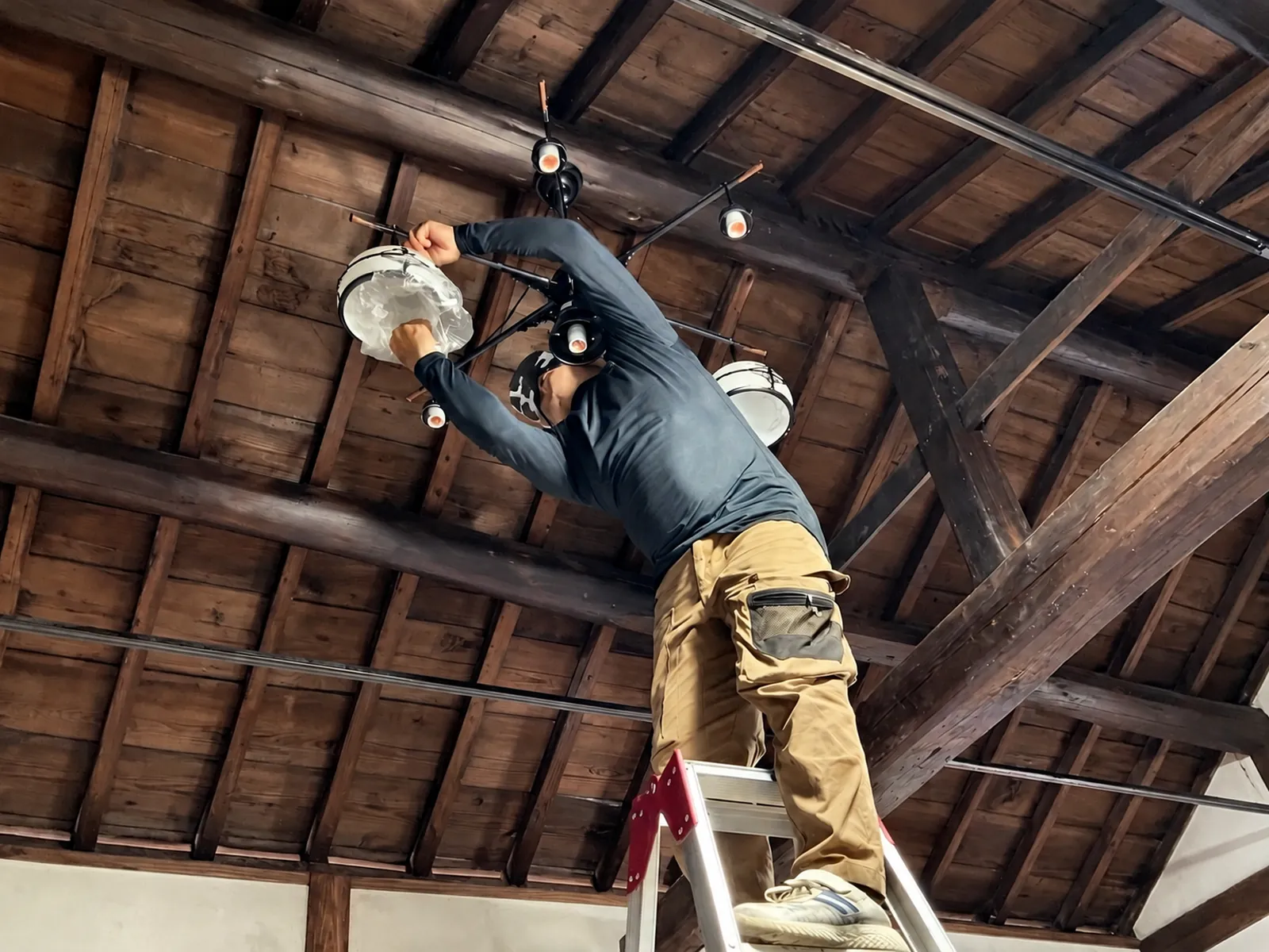 梁の下で照明器具を取り付ける職人